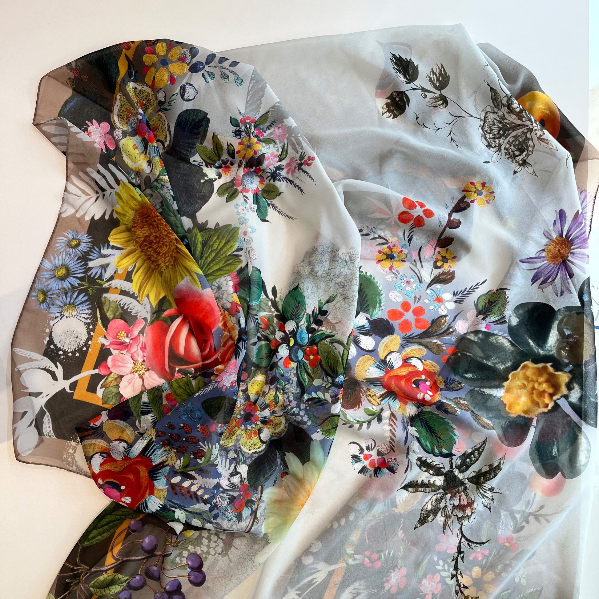 Foulard mit floralen Motiven und filigranen Details, gestaltet mit bunten Blumen, Blättern und einem eleganten Rahmen, ideal als stilvolles Accessoire.